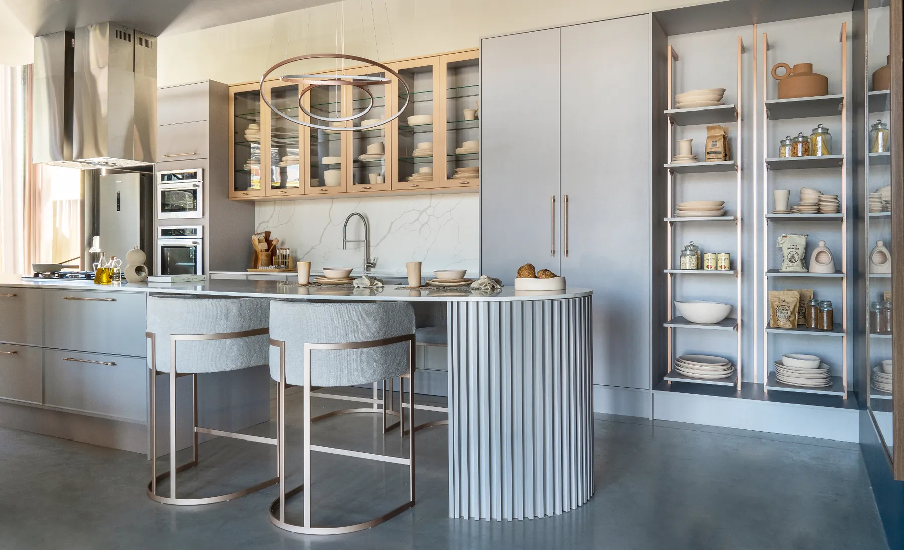 Cozinha planejada com marcenaria em madeira nobre, ilha em mármore e pendentes escultóricos